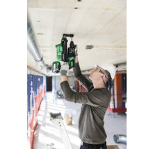 Ein Mann bohrt mit einem Akku-Bohrhammer in eine Betondecke auf einer Baustelle.