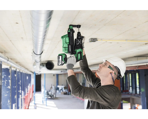 Ein Mann in Schutzkleidung verwendet einen Akku-Bohrhammer von HiKoki an einer Decke.