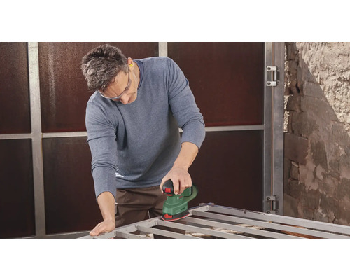 Mann schleift Metallrahmen mit Schleifgerät