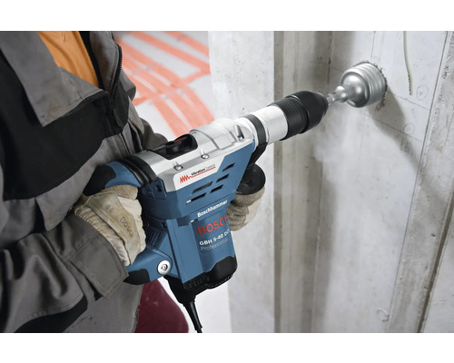 Ein Mann bohrt mit einem Bosch Bohrhammer ein Loch in eine Betonwand.