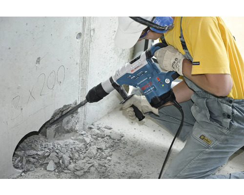 Ein Arbeiter benutzt einen Bohrhammer, um ein Loch in eine Betonwand zu bohren.