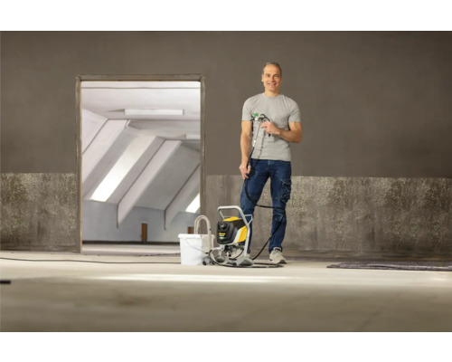 Mann mit Farbspritzgerät in einem leeren Raum