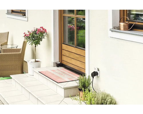 Eingangsbereich eines Hauses mit Außentreppe, Tür, Pflanzen und Außensteckdose