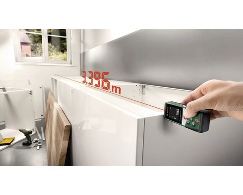 Hand mit Bosch Laser-Entfernungsmesser bei der Messung eines Möbels