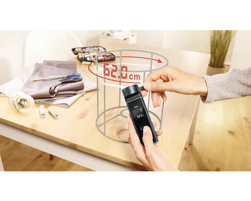 Person misst Lampenschirm mit digitalem Messgerät auf einem Tisch