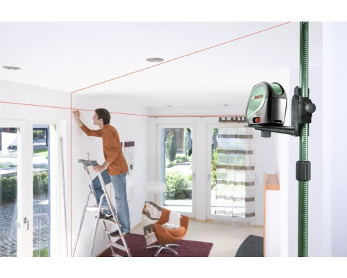 Mann benutzt einen Linienlaser im Innenraum zur Ausrichtung an einer Wand.