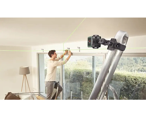 Ein Mann befestigt eine Halterung an der Decke mit Hilfe eines Linienlasers und einer Leiter.