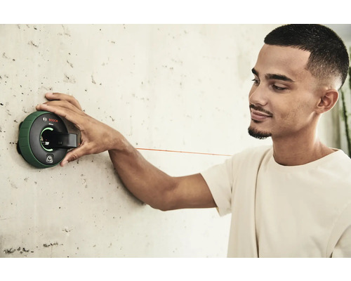 Ein Mann befestigt einen Linienlaser an einer Wand.