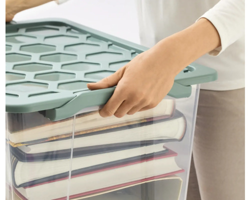 Person verschließt eine gefüllte, durchsichtige Aufbewahrungsbox mit Deckel