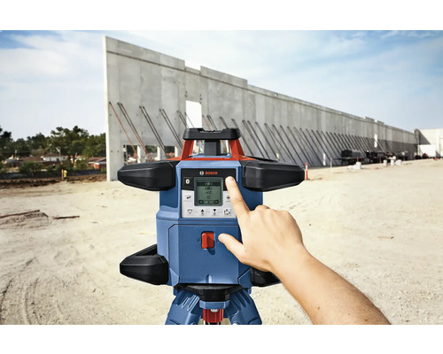 Bosch Logo. Rotationslaser auf einer Baustelle mit einer Hand, die den Bildschirm berührt.