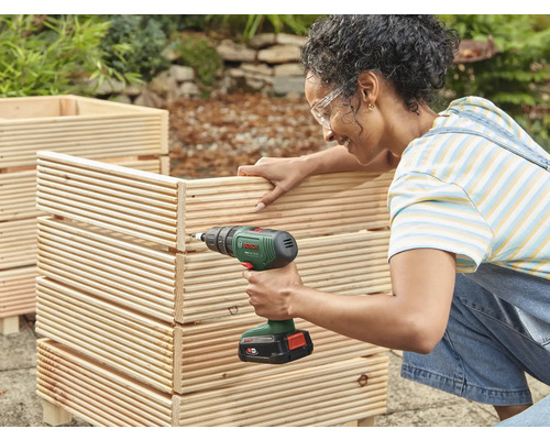 Frau schraubt mit Akkuschrauber Holzkasten zusammen