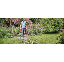 Mann benutzt einen Laubsauger im Garten.