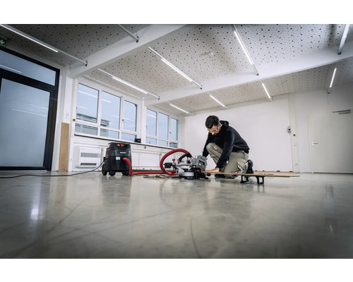 Eine Person arbeitet mit einer Kappsäge und einem Staubsauger in einem hellen Raum.