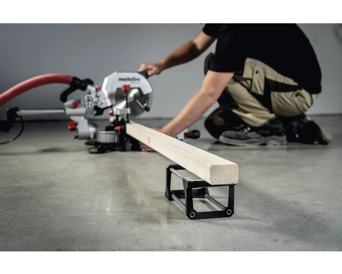 Eine Metabo Kappsäge schneidet ein Werkstück aus Holz. Eine Person bedient die Säge.