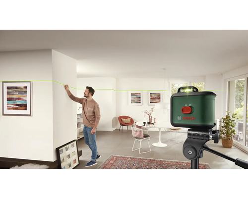 Mann benutzt Bosch Kreuzlinienlaser in einem hellen Wohnraum.