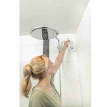 Frau reinigt Duschkopf mit Reinigungsspray im Badezimmer.