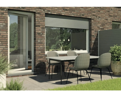 Außenbereich mit Rollladen, Terrassentür und Gartentisch mit Stühlen.