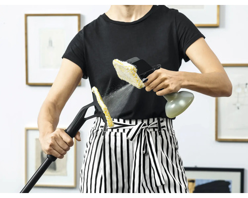 Eine Person benutzt einen Dampfreiniger mit verschiedenen Aufsätzen zur Reinigung in einem Innenraum.