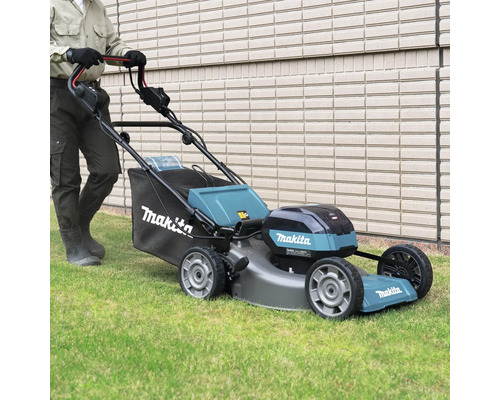 Eine Person benutzt einen Makita Akku-Rasenmäher auf einem Rasen