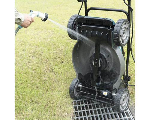 Eine Rasenwalze wird mit einem Wasserschlauch gereinigt.