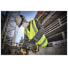 Ein Bauarbeiter verwendet einen Winkelschleifer auf einer Baustelle und trägt dabei Schutzkleidung.