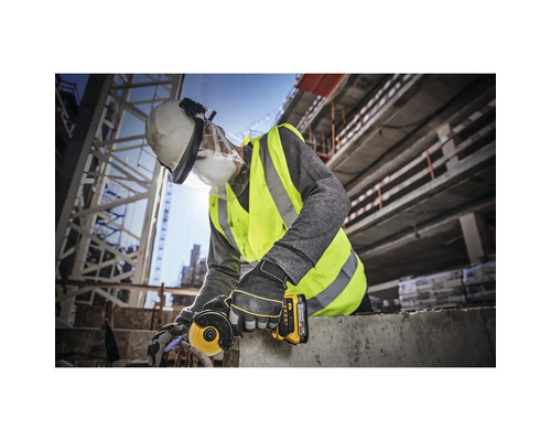 Ein Bauarbeiter verwendet einen Winkelschleifer auf einer Baustelle und trägt dabei Schutzkleidung.