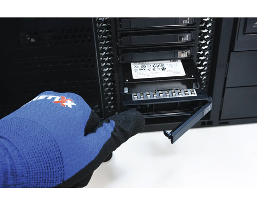 Eine Person mit Handschuhen installiert eine SSD in einem Computergehäuse.
