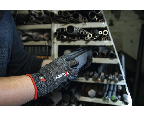 Eine Person trägt KinetiXx Arbeitshandschuhe und entnimmt ein Metallstück aus einem Regal mit Metallrohren.
