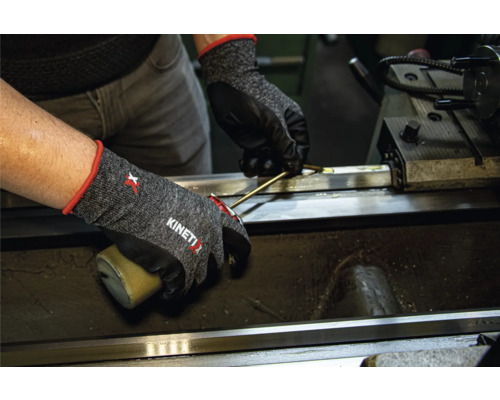 Person mit KinetiXx Arbeitshandschuhen bei der Arbeit an einer Maschine.