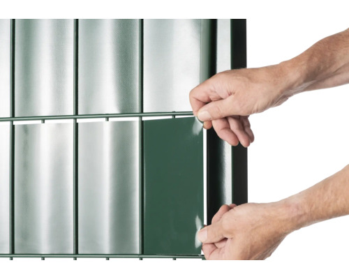 Detailansicht eines Zauns mit Sichtschutzstreifen und einer Person, die einen Streifen anbringt