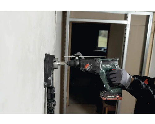 Ein Handwerker bohrt mit einem Metabo Bohrhammer ein Loch in eine Wand.