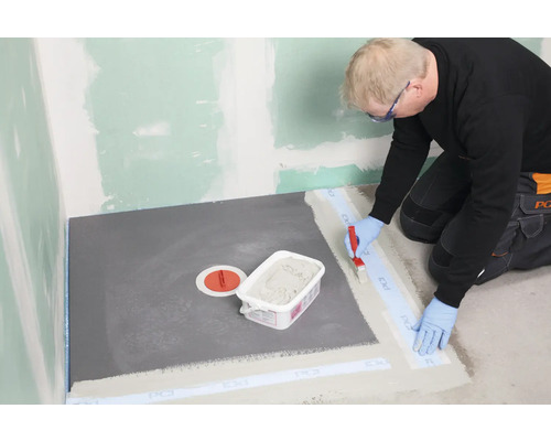 Handwerker dichtet eine Dusche mit Dichtband und Dichtschlämme ab