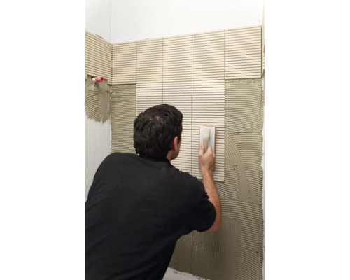 Fliesenleger bei der Arbeit: Anbringen von Wandfliesen im Badezimmer.