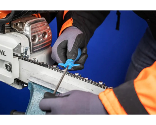 Eine Person schärft eine Kettensäge mit einem Werkzeug.