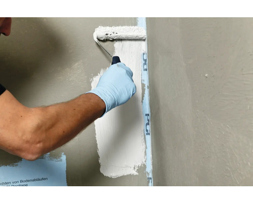 Anstreichen einer Wand mit einer Farbwalze neben einem Abdichtband
