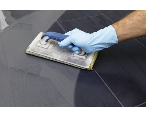 Fliesenleger mit Reinigungsschwamm zum Reinigen von Fliesen