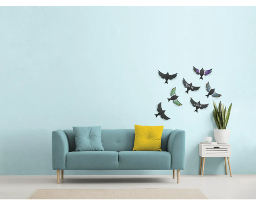 Wohnzimmer mit Sofa, Kissen, Wanddekoration mit Vogelmotiven und Beistelltisch mit Pflanze
