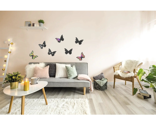 Wohnzimmer mit grauer Couch, Kissen, Teppich, Tisch, Stuhl, Wanddekoration und Zimmerpflanzen für eine gemütliche Atmosphäre.