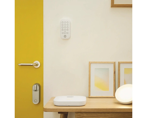 Szene mit digitalem Türschloss, Tastenfeld, Basisstation und Bilderrahmen auf einem Tisch