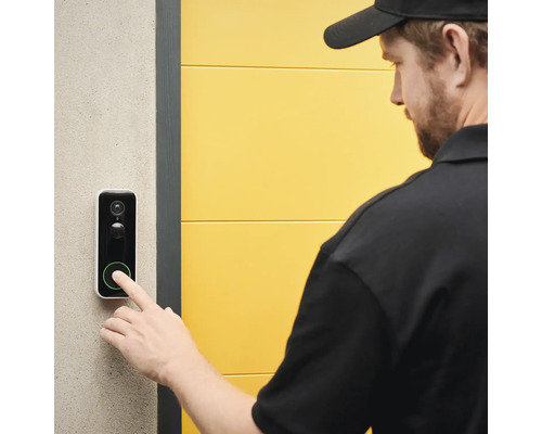 Eine Person drückt auf eine Türklingel mit Kamerafunktion.