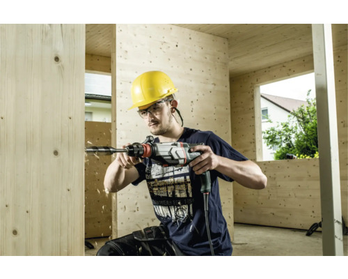 Mann bohrt mit einer Bohrmaschine ein Loch in eine Holzwand