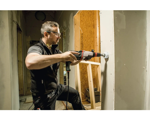 Ein Mann bohrt mit einer Metabo Bohrmaschine ein Loch in eine Trockenbauwand.