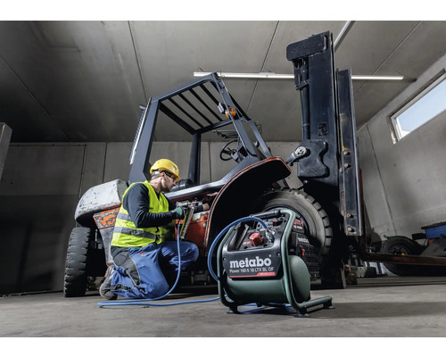Ein Arbeiter repariert einen Gabelstapler mit einem Metabo Kompressor in einer Werkstatt.