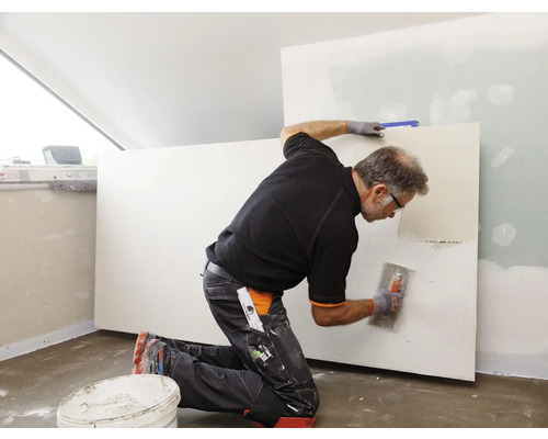Handwerker spachtelt eine Trockenbauwand mit einer Glättkelle