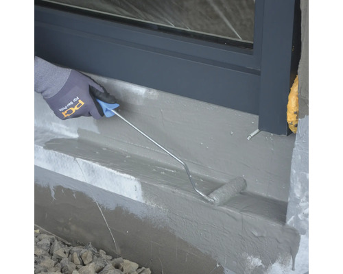 Auftragen einer Abdichtung mit einer Walze an einer Hauswand.