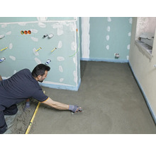 Handwerker glättet Estrich in einem Badezimmer mit einer Glättkelle