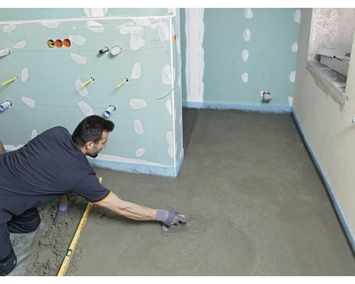 Handwerker glättet Estrich in einem Badezimmer mit einer Glättkelle