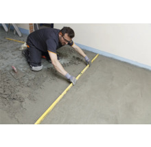 Handwerker nivelliert Estrich mit einer Richtlatte.