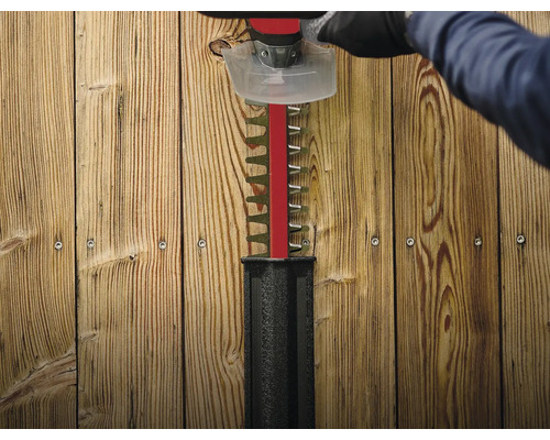 Heckenschere im Einsatz vor Holzzaun