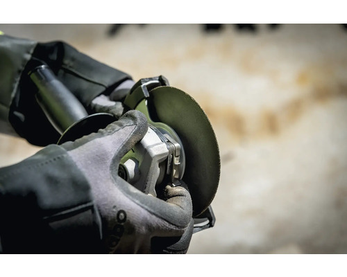 Blick auf eine Person, die mit einem Winkelschleifer arbeitet und Schutzhandschuhe trägt